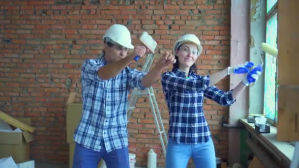 Iki genç erkek ve kadın eğlenceli dans kask ve bir tuğla duvar arka planı — Stok video
