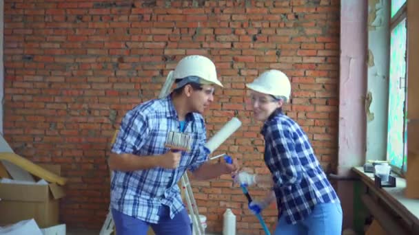 Feliz pareja de hombres y mujeres jóvenes cantando y bailando durante las reparaciones — Vídeos de Stock