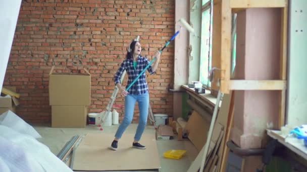 Expressieve vrolijk meisje dansen en zingen tijdens de reparatie — Stockvideo