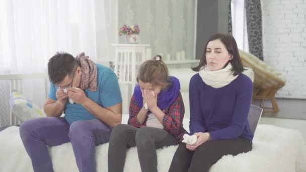 The family has a cold, mom dad and daughter sneeze sitting at home on the bed — Stock Video