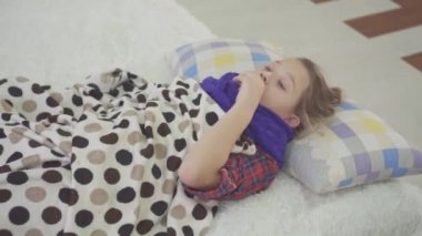 küçük kız yatakta soğuk evde, güçlü öksürük, boğaz ağrısı vardır
