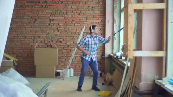 Energetic and contented man in a shirt paints the walls during an apartment renovation — Stock Footage Energetic Contented Man Shirt Paints Walls Apartment Renovation Royalty Free Stock Footage