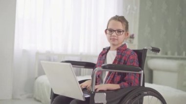 bir dizüstü bilgisayar kullanarak bir tekerlekli sandalye bir genç engelli kız portresi