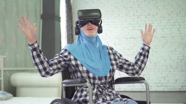 Женщина в хиджабе, инвалидное кресло, использует очки VR, 3D технологии — стоковое видео