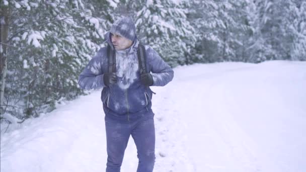 Retrato hombre congelado en la nieve, caminando por el bosque con una mochila — Vídeos de Stock