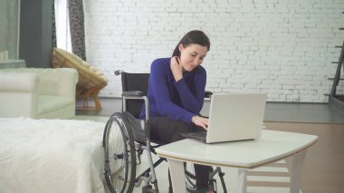 portre genç gülümseyen güzel kadın bir tekerlekli sandalye, evde çalışan bir dizüstü bilgisayarda, Internet uzaktan çalışma devre dışı