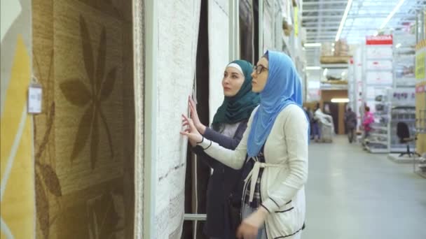 Two arab young women in hijab choose carpet — Stock Video