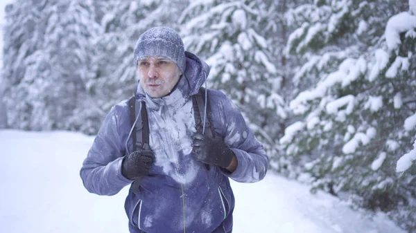 Adam kış orman kar ile kaplı bir sırt çantası ile dondurulmuş portre. — Stok fotoğraf