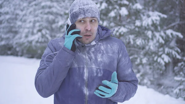 Frozen man in the winter forest talking on the phone