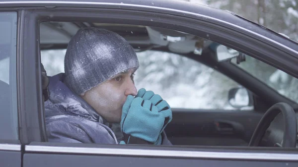Заморожений чоловік сидить у машині і зігріває руки — стокове фото