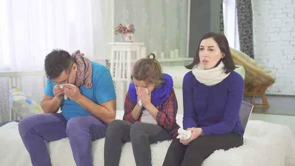 The family has a cold, mom dad and daughter sneeze sitting at home on the bed — Stock Photo, Image