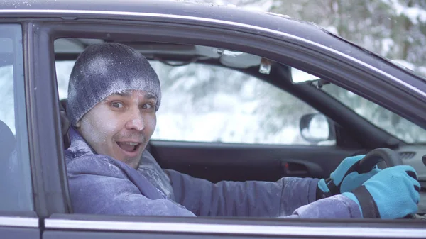 Hombre congelado alegre sentado en el coche y mirando a la cámara Imagen De Stock