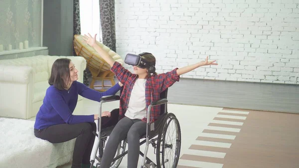 Disabled teenager in a wheelchair and her mom at home using vr technology Royalty Free Stock Photos