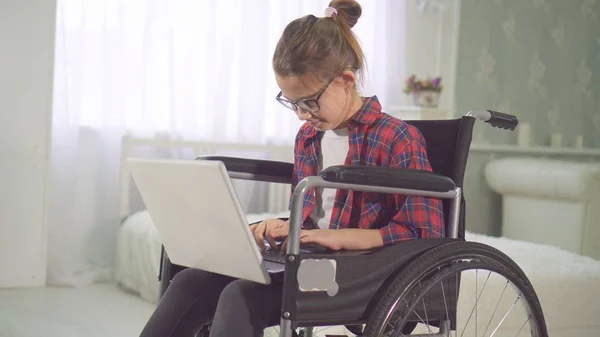 Portrait of a teenage disabled girl in a wheelchair using a laptop Royalty Free Stock Images