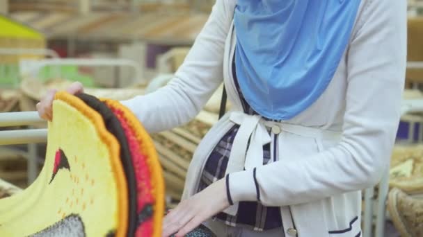 Wanita muslim muda dalam jilbab dan kacamata di sebuah toko karpet — Stok Video