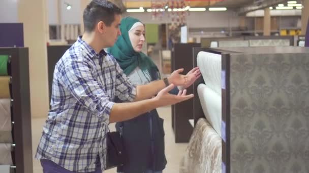 Mladý muslimský pár zvolit tapetu v úložišti pro opravu — Stock video