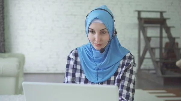 Joven hermosa mujer en hijab con auriculares y auriculares, centro de cal trabajador Imagen De Stock