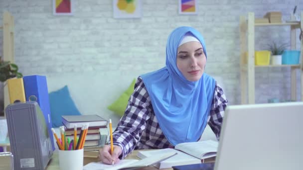 Mooie jonge moslimvrouw in hijab, studeren in moderne appartementen portret — Stockvideo