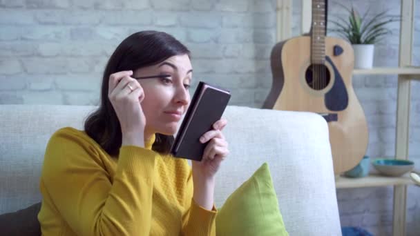 Fiatal nő apartman csinál csinál-ig, a kanapén — Stock videók