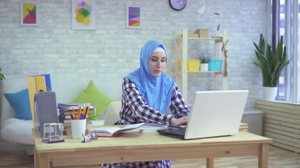 美しい若いイスラム教徒の女性、ヒジャーブのモダンなアパートメントでの勉強 — ストック動画