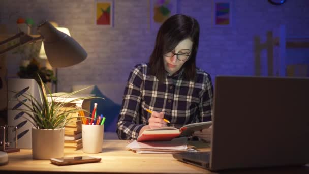 Молода жінка працює пізно в своїй сучасній квартирі для ноутбука — стокове відео