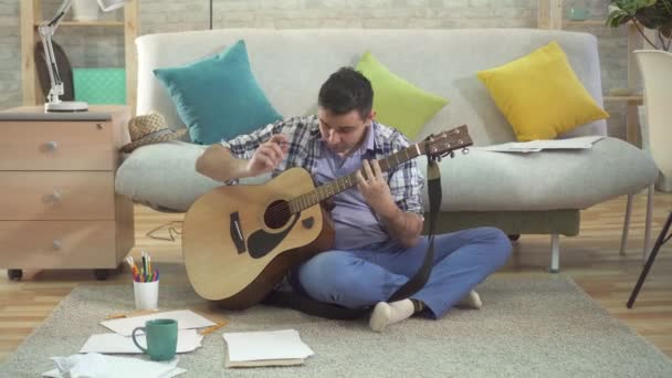 Jonge Creative man muzikant gitaar spelen en het schrijven van een lied — Stockvideo