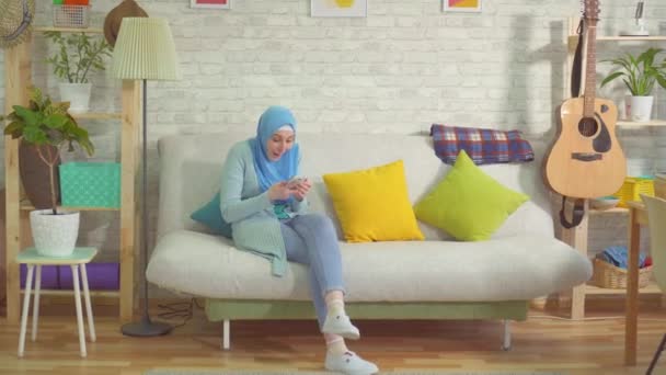 Bella donna musulmana in un hijab impara a vincere con uno smartphone e balla — Video Stock