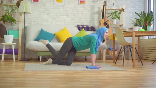 Спортивная мусульманка в хиджабе делает упражнения в современной квартире — стоковое видео
