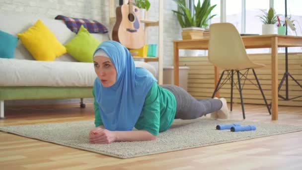 Femme musulmane sportive en hijab fait planche dans un appartement moderne — Video