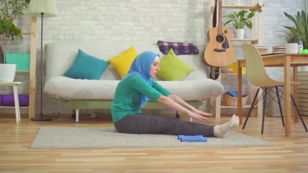 Sportliche muslimische Frau im Hijab beim Aufwärmen in einer modernen Wohnung — Stockvideo