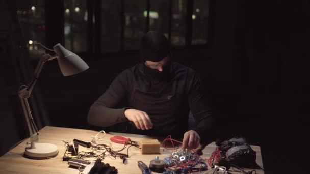 Unrecognizable terrorist wearing a balaclava mask making a bomb — Stock Video