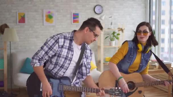 Porträt einer jungen Frau und eines jungen Mannes, die emotional Gitarre spielen und tanzen — Stockvideo