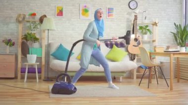 Hijab Müslüman kadın bir gitarist olarak bir elektrikli süpürge dans ile etrafında kandırıyor