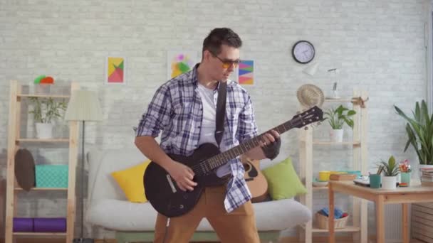 Retrato joven músico con gafas tocando emocionalmente la guitarra eléctrica — Vídeo de stock