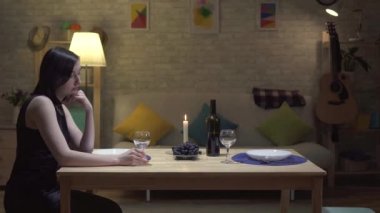 Mum ışığında ve ağlayan modern bir evde bir masada oturan yalnız sevimli esmer