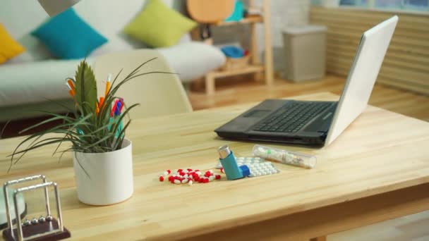 Таблетки от аллергии и астматический ингалятор на столе в современной квартире — стоковое видео