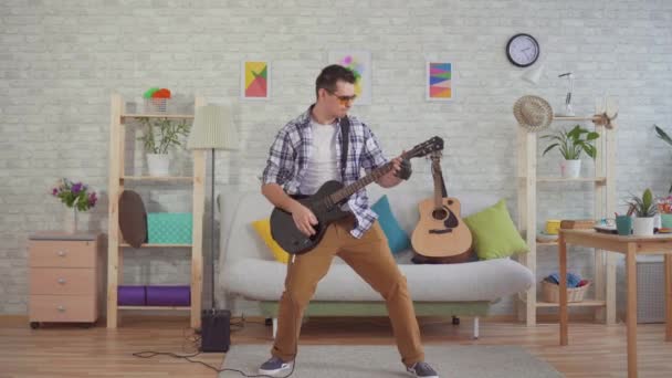 Junger Mann mit Brille spielt emotional E-Gitarre — Stockvideo