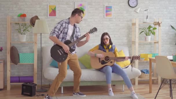 Młoda kobieta i młody mężczyzna emocjonalnie gra na gitarze — Wideo stockowe