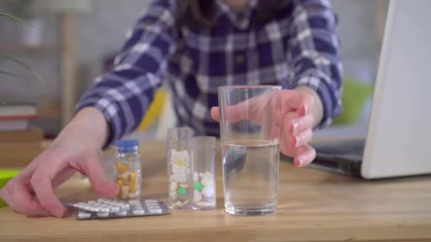 Mujer joven sentada con portátil bebiendo medicamentos contra la gripe — Vídeos de Stock