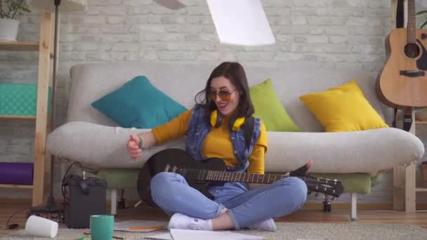若い女性ロッカーミュージシャンは、床に座ってエレキギターを演奏感情的 — ストック動画