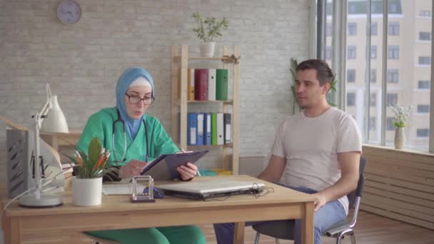 Bir hijab bir Müslüman doktor resepsiyonunda Arap adam — Stok video