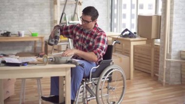 Bir elektrikli matkap ile tekerlekli sandalyede özürlü genç adam onarım meşgul