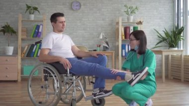 Doktor, Engelli bir kişinin bacağını tekerlekli sandalyede inceliyor
