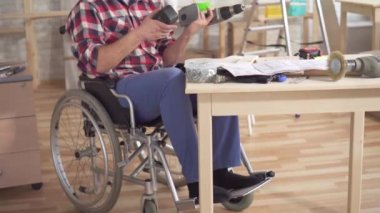 Eldeki elektrikli tornavidayla tekerlekli sandalyede özürlü bir adamın portresi