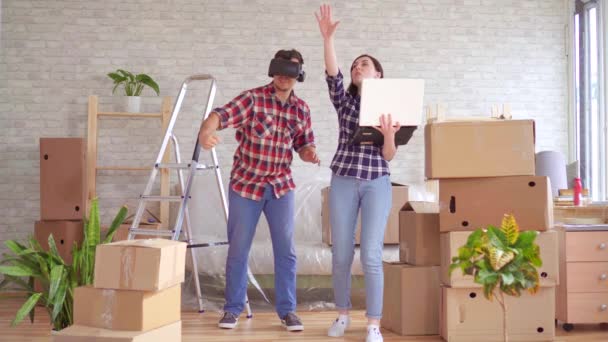 Jeune femme avec un ordinateur portable montre un homme en lunettes VR le projet d'un nouvel appartement — Video