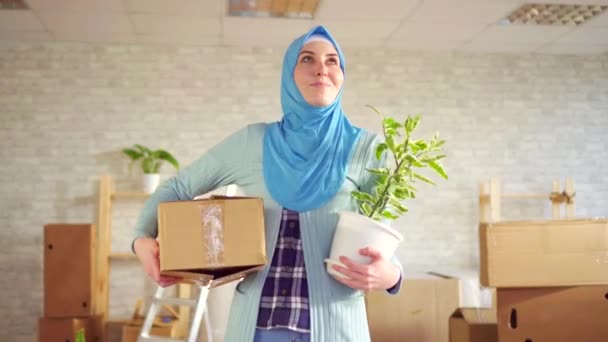 Porträtt ung muslimsk kvinna i en hijab med en blomma och en låda i hennes händer — Stockvideo