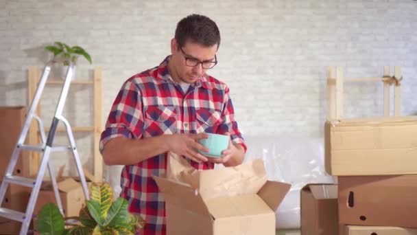 Чоловік розпаковує коробку посуду під час руху і знаходить пошкодження — стокове відео