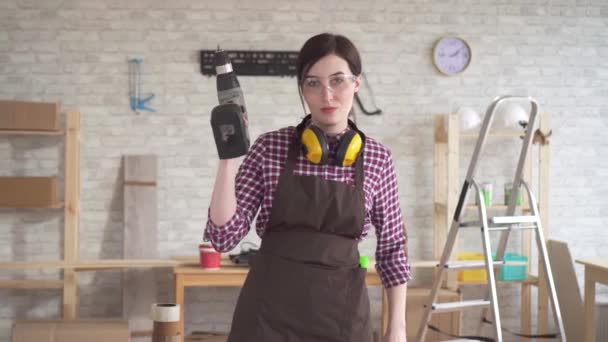 Portrait professional young worker carpenter woman with an electric drill — Stock Video