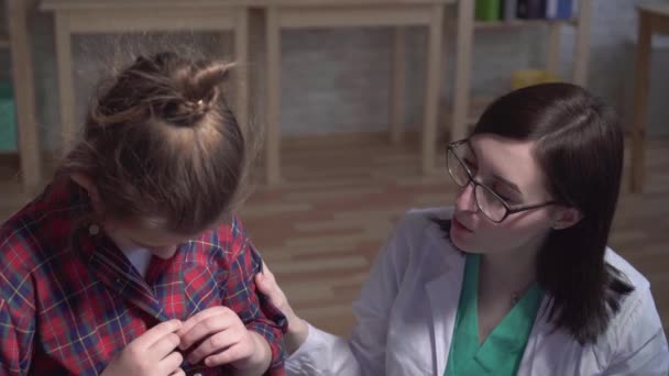 Tiro dramático de uma criança doente e um médico de casaco branco conversando com um paciente da clínica — Vídeo de Stock