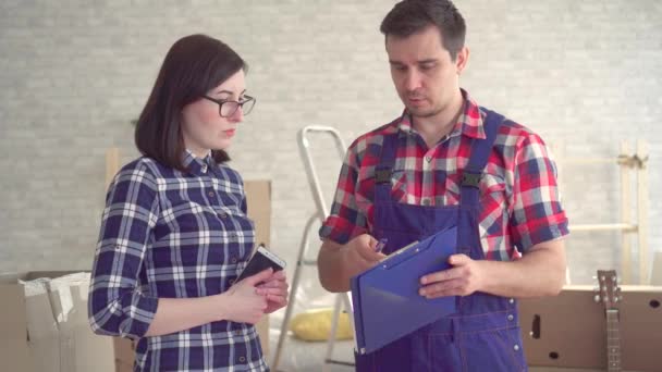 Homme chargeur en uniforme et jeune femme sur le fond de boîtes pour déménager nouvelle maison — Video